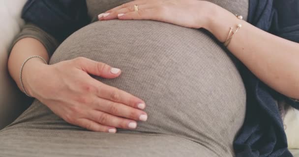 A ligar-me ao meu bebé. Filmagem 4K de uma mulher esfregando sua barriga grávida enquanto relaxa em seu sofá em casa. — Vídeo de Stock