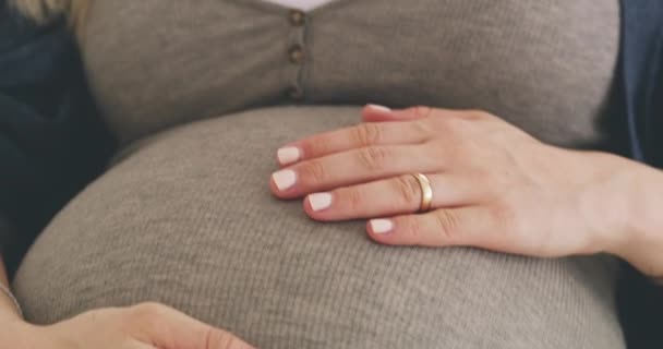 Eu vou ser uma mãe. Filmagem 4K de uma mulher esfregando sua barriga grávida enquanto relaxa em seu sofá em casa. — Vídeo de Stock