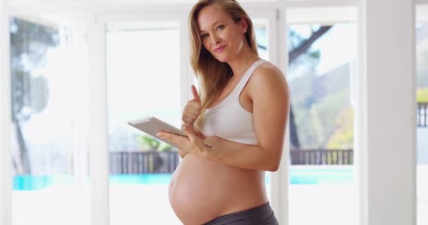 Acompanhe a gravidez semana após semana. Filmagem 4K de uma mulher grávida usando seu tablet digital em casa. — Vídeo de Stock