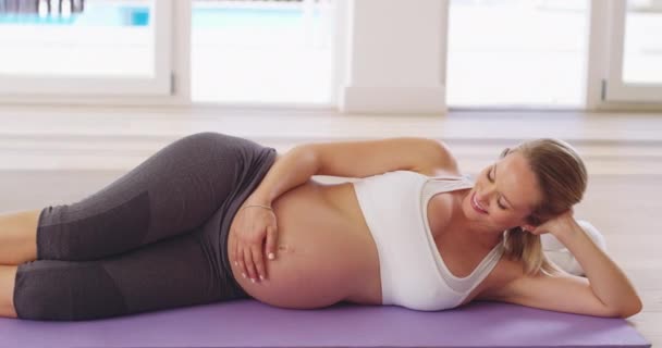 Şimdi bir molaya ihtiyacımız var. Hamile bir kadının antrenmandan sonra yoga minderinde dinlendiği 4K video görüntüsü.. — Stok video