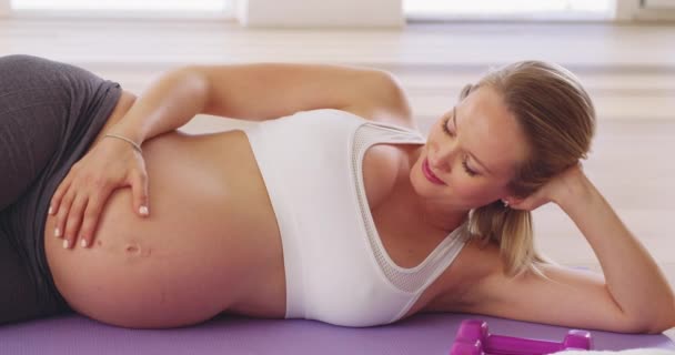 宝宝喜欢那一个。4k段关于一名孕妇运动后在瑜伽垫上放松的视频. — 图库视频影像