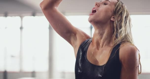To dopiero orzeźwiające. 4k wideo atrakcyjnej młodej kobiety wylewającej na siebie wodę po treningu na siłowni. — Wideo stockowe