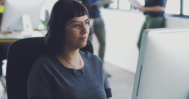Completamente centrada en su trabajo. Imágenes de vídeo 4K de una joven diseñadora que trabaja en su ordenador en una oficina moderna. — Vídeo de stock