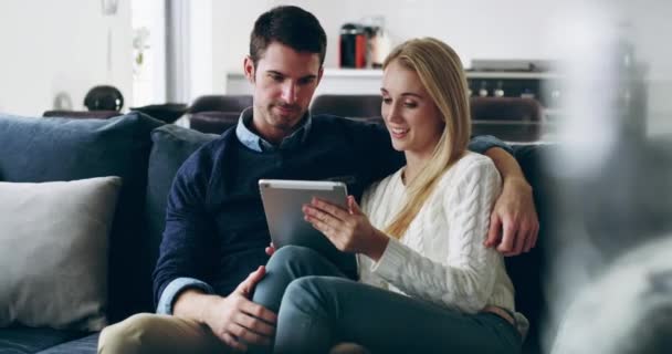 Blijf binnen, blijf verbonden. 4K video beelden van een liefdevol jong paar met behulp van een digitale tablet samen op de bank thuis. — Stockvideo