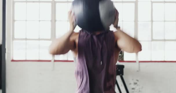 Kasta dig själv på dina mål. 4k video av en muskulös ung man som tränar med en träningsboll på gymmet. — Stockvideo