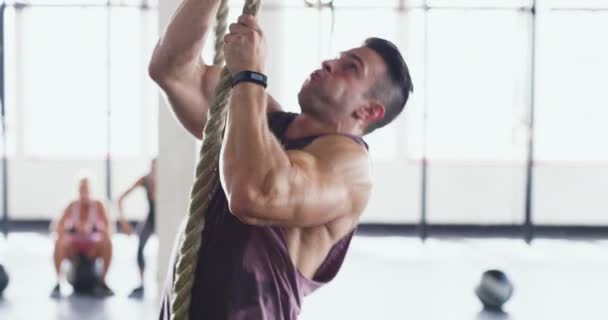 Auf dem Weg zu seinen Fitness-Zielen. 4k-Video eines muskulösen jungen Mannes beim Seilklettern in der Turnhalle. — Stockvideo