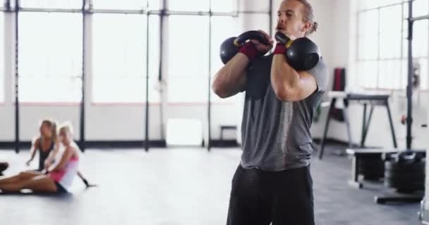 Makt och uthållighet. 4k video av en muskulös ung man som tränar med kettlebells i gymmet. — Stockvideo