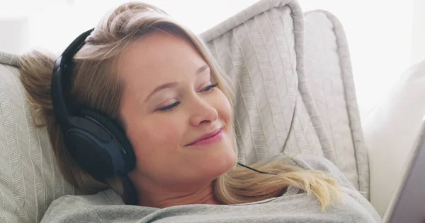 Muziek heeft helende mogelijkheden. 4k video van een vrouw luisteren naar muziek terwijl ontspannen op haar bank. — Stockfoto