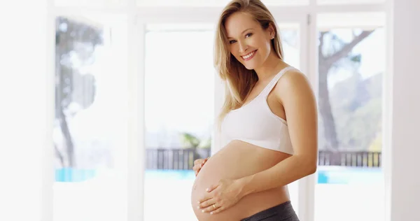 O pequenino vem primeiro. Retrato recortado de uma jovem mulher grávida atraente esfregando sua colisão de bebê. — Fotografia de Stock
