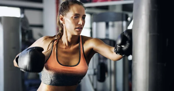 Impacchetta un pugno. Ritaglio di una giovane pugile che si allena su un sacco da boxe in palestra. — Foto Stock