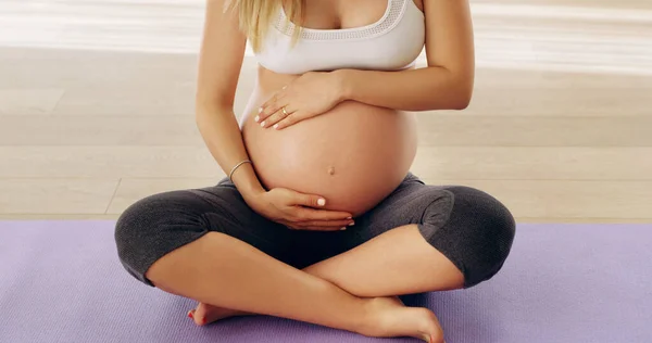 Θα σε φροντίσω εγώ. Τραβηγμένο πλάνο μιας αγνώριστης νεαρής εγκύου που τρίβει το μωρό της ενώ κάθεται σε ένα στρώμα γιόγκα.. — Φωτογραφία Αρχείου