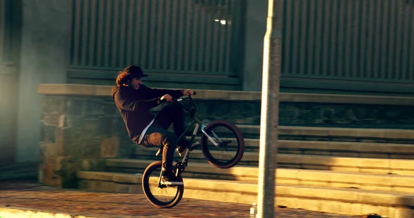 A abrir uma rodinha. Filmagem completa de um jovem piloto BMX do sexo masculino fazendo truques em torno da cidade. — Fotografia de Stock