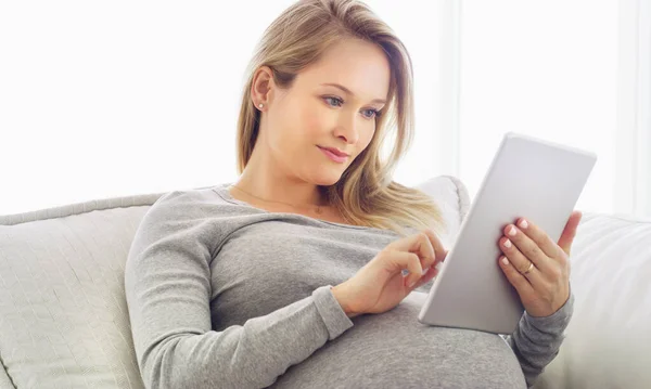 Ottenere alcuni consigli sulla gravidanza online. Colpo di una donna incinta che usa una tavoletta a casa. — Foto Stock