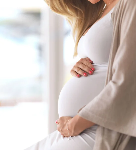 Son bébé est entre des mains aimantes. Plan recadré d'une femme enceinte méconnaissable assise à la maison. — Photo