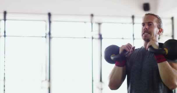4k wideo muskularnego młodzieńca ćwiczącego z kettlebells na siłowni. — Wideo stockowe
