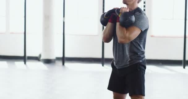 Han pratar om hissen. 4k video av en muskulös ung man som tränar med kettlebells i gymmet. — Stockvideo