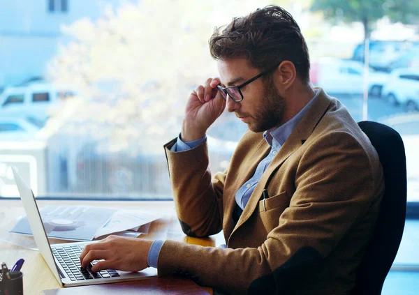 Un autre jour au bureau. Prise de vue d'un bel homme d'affaires travaillant sur un ordinateur portable assis à son bureau dans le bureau. — Photo