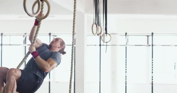 Достижение новых высот. 4k видео мускулистого молодого человека, карабкающегося по веревке во время тренировки в спортзале. — стоковое видео