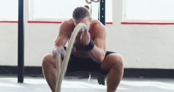 Bitva je jen proti tobě. 4k video svalnatý mladý muž cvičit s těžkými provazy v tělocvičně. — Stock video