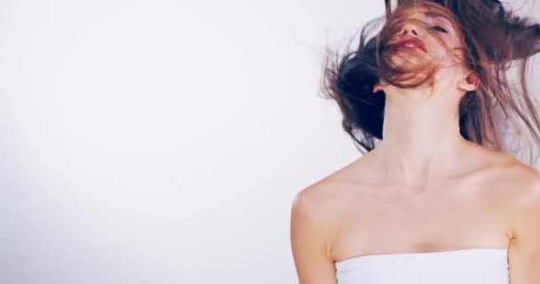 Uwielbiam moją nową fryzurę. 4k wideo z piękną młodą kobietą pstrykającą włosami w studiu. — Wideo stockowe