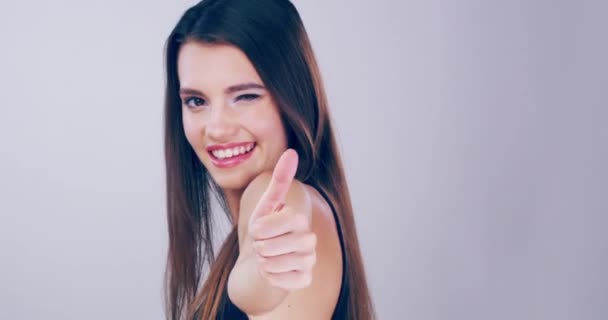 Pulgares para cuidar tu piel. Imágenes de video de 4k de una hermosa joven con un hermoso cabello mostrando los pulgares en el estudio. — Vídeos de Stock