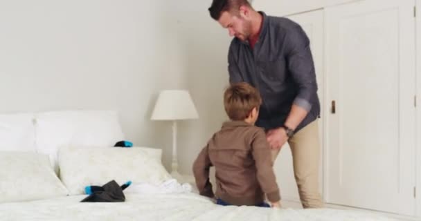 Vestir-se é o primeiro passo do dia. 4k vídeo metragem de um belo jovem pai vestindo seu filho em casa. — Vídeo de Stock
