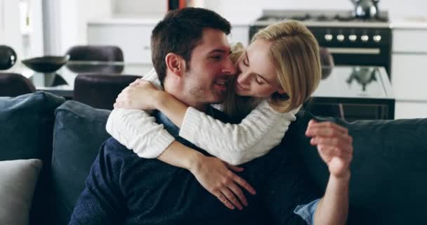 Generoso com o seu afecto. Filmagem em vídeo 4K de um jovem casal feliz compartilhando um momento afetuoso em casa no sofá. — Vídeo de Stock
