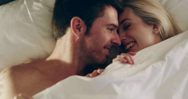Hemmelige elskere. 4K video optagelser af et lykkeligt ungt par under dækslerne i sengen derhjemme. – Stock-video