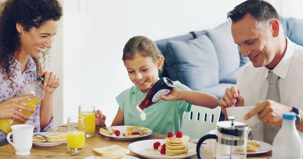 Commencez chaque matin avec les gens qui comptent le plus. Tourné d'une jolie petite fille prenant le petit déjeuner avec ses parents le matin à la maison. — Photo