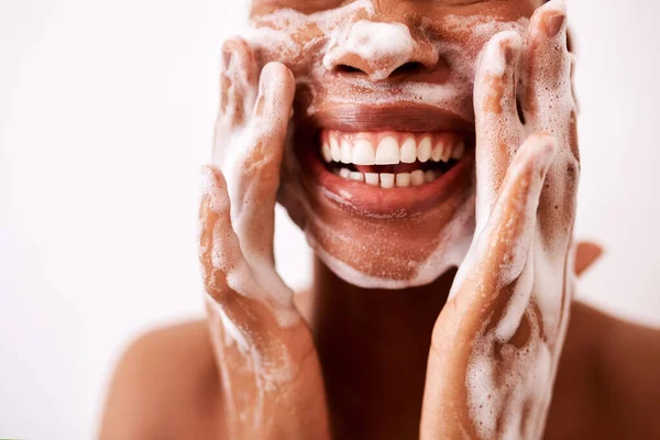 Utrzymanie mojej skóry w czystości sprawia, że wygląda to dobrze. Studio ujęcie nierozpoznawalnej kobiety myjącej twarz na białym tle. — Zdjęcie stockowe