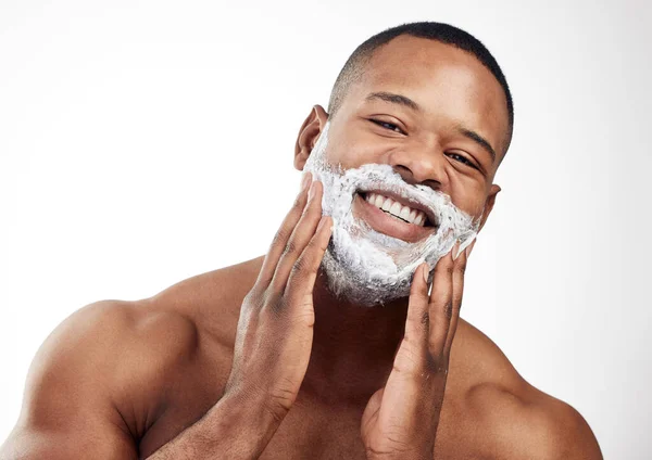 Formando uma almofada espumosa no rosto antes de fazer a barba. Estúdio retrato de um jovem bonito aplicando creme de barbear em seu rosto contra um fundo branco. — Fotografia de Stock