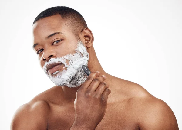 Pürüzsüz ve parlak cilt için doğru tıraş ürünlerini kullanın. Beyaz arka planda sakallarını tıraş eden yakışıklı bir gencin stüdyo portresi.. — Stok fotoğraf
