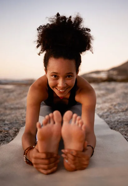 你必须保持柔软。一位迷人的年轻女子日落时在海滩上练习瑜伽的全长肖像. — 图库照片
