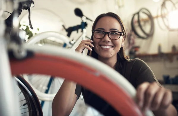 네 자전거받았는지 확인하려고 전화했어. 자전거 가게에 웅크리고 앉아 핸드폰을 사용하는 매력적 인 젊은 여성의 사진. — 스톡 사진