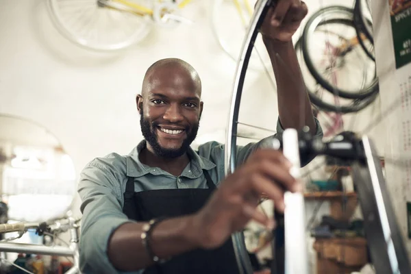 Me encanta lo que hago. Disparo de un joven guapo parado solo en su tienda y reparando una rueda de bicicleta. — Foto de Stock