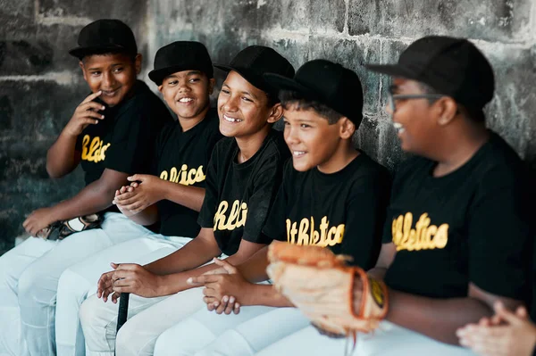 Beyzbol, çocukları aktif ve sosyal olarak meşgul tutmak için harika bir yoldur. Bir grup genç beyzbolcunun bir oyun sırasında bankta yan yana oturdukları sahneler.. — Stok fotoğraf