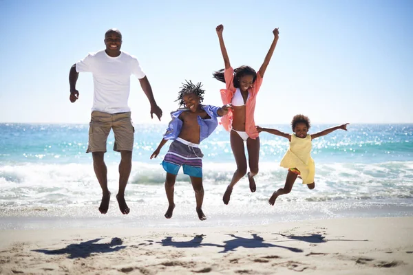 Woohoo Tempo di vacanza spacca. Una famiglia afroamericana eccitata che salta in aria sulla spiaggia con un bellissimo oceano sullo sfondo. — Foto Stock