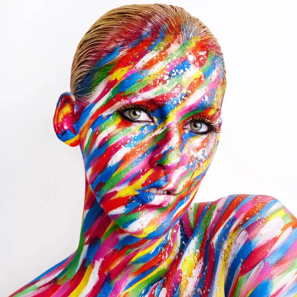 Bold is beautiful. Studio shot of a young woman posing with brightly colored paint on her face against a white background. — Stock Photo, Image