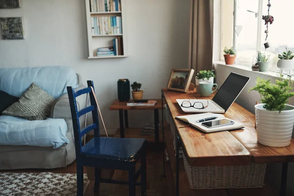 Welkom in mijn kantoor. Gesneden shot van technologie en een notebook op een bureau in een leeg thuiskantoor gedurende de dag. — Stockfoto