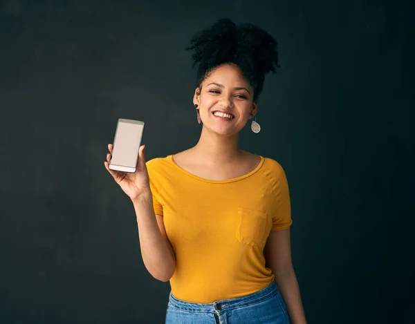 이 놀라운 모바일 앱을 보 세요. 회색 배경에 대고 포즈를 취하면서 핸드폰을 들고 있는 젊은 여성의 사진. — 스톡 사진