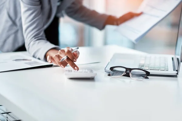 Mettre les chiffres en perspective. Plan recadré d'une femme d'affaires utilisant une calculatrice à son bureau dans un bureau moderne. — Photo