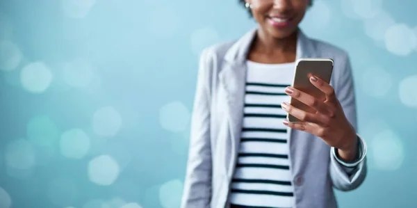 Faz contacto e faz com que aconteça. Fotografia de estúdio recortada de uma jovem empresária usando um telefone celular contra um fundo azul. — Fotografia de Stock