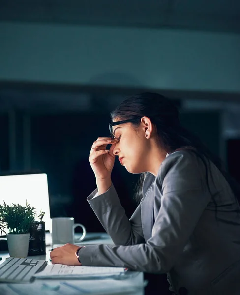 Horas extras podem vir com dores de cabeça. Tiro de uma jovem empresária experimentando uma dor de cabeça no escritório. — Fotografia de Stock