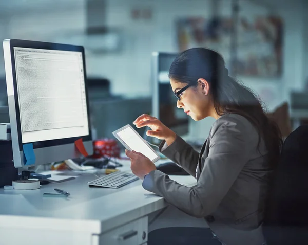 Online en op het werk. Een foto van een jonge zakenvrouw die laat op kantoor werkt.. — Stockfoto