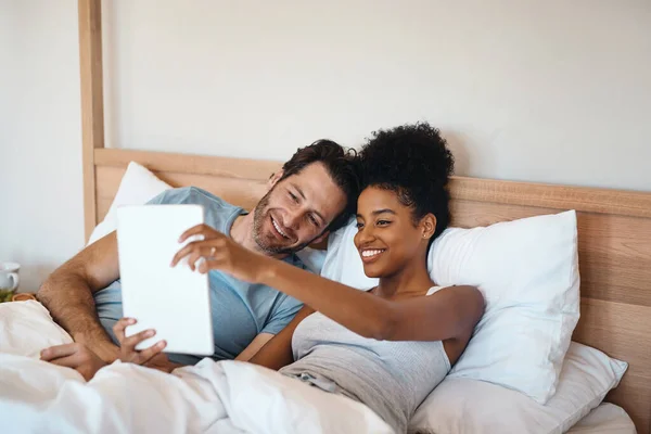 방금 막 이 에피소드를 보기 시작 했습니다. 침대에 누워 있는 남녀를 디지털 태블릿으로 찍은 사진. — 스톡 사진