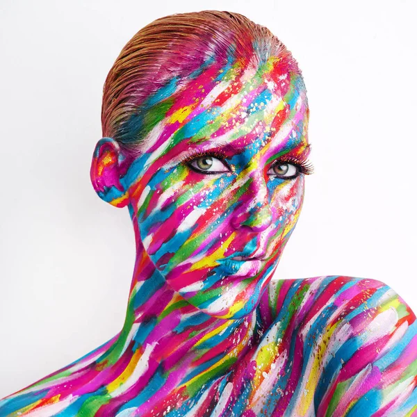 Hay arte en la belleza. Foto de estudio de una joven posando con pintura de colores brillantes en su cara sobre un fondo blanco. —  Fotos de Stock