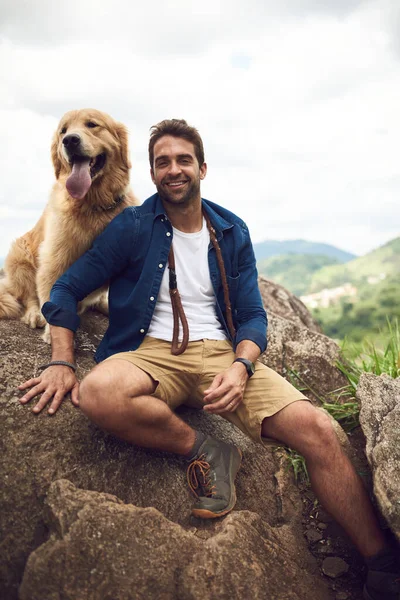 我们只是喜欢爬山。一个英俊的年轻人和他的狗在爬山时正在休息的肖像画. — 图库照片