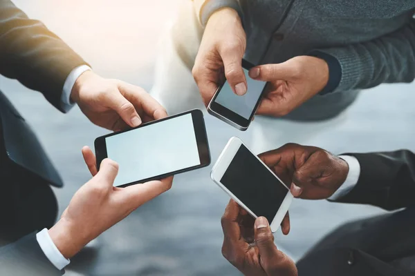 Das Geschäft läuft besser, wenn man vernetzt ist. Aufnahme einer Gruppe unkenntlich gemachter Geschäftsleute mit ihren Mobiltelefonen im Büro. — Stockfoto