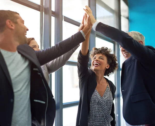 A positividade gera sucesso. Tiro de um grupo de colegas dando uns aos outros um alto cinco. — Fotografia de Stock