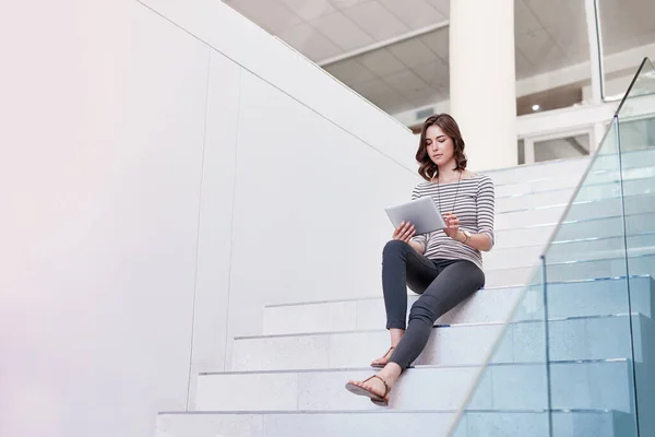 Melhorar a visibilidade online com tecnologia moderna. Tiro de uma jovem empresária usando um tablet digital nas escadas em um escritório moderno. — Fotografia de Stock
